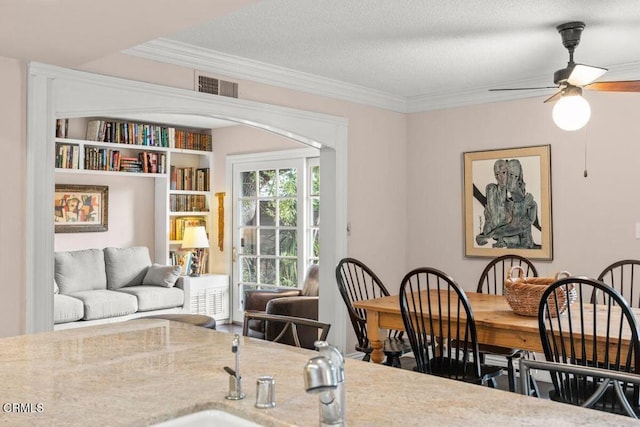 dining space with ceiling fan, crown molding, and a textured ceiling