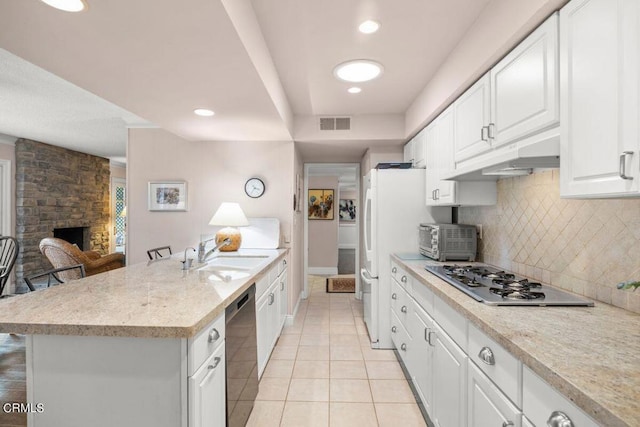 kitchen with sink, white cabinetry, stainless steel gas cooktop, dishwasher, and a stone fireplace