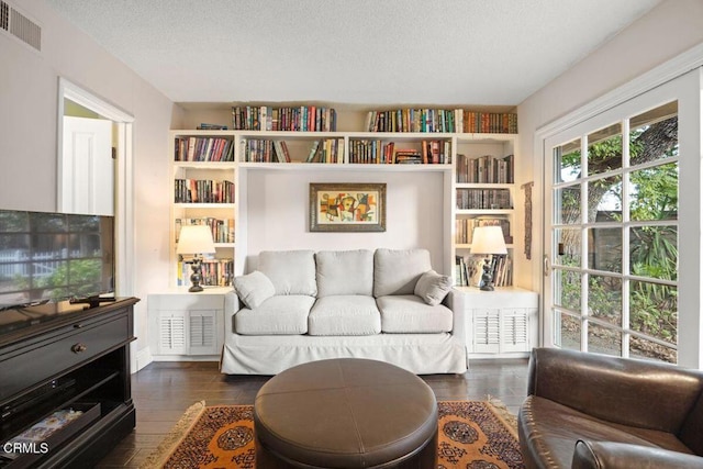 sitting room with dark wood-type flooring, a textured ceiling, and built in features