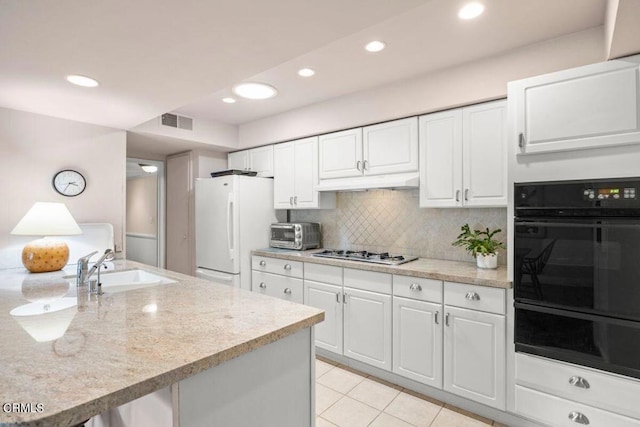 kitchen featuring white refrigerator, sink, white cabinetry, decorative backsplash, and stainless steel gas stovetop