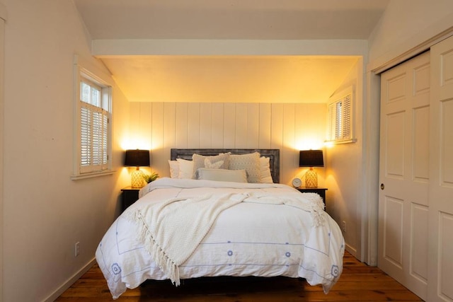 bedroom with a closet, dark hardwood / wood-style flooring, and vaulted ceiling