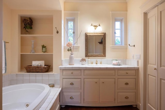 bathroom featuring tiled tub, vanity, and a healthy amount of sunlight