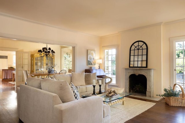 living room with wood-type flooring, crown molding, a wealth of natural light, and a chandelier