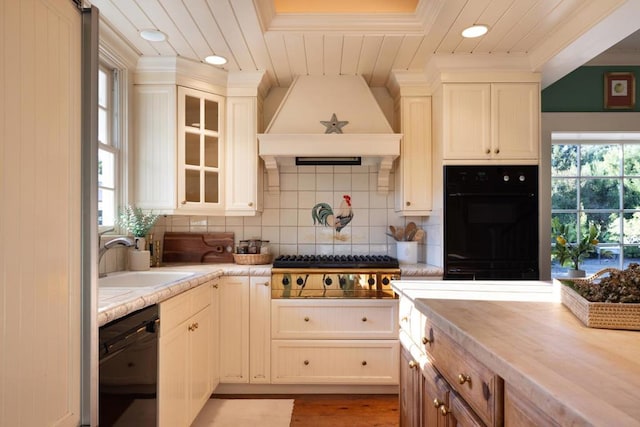 kitchen with sink, wood counters, backsplash, black appliances, and custom range hood