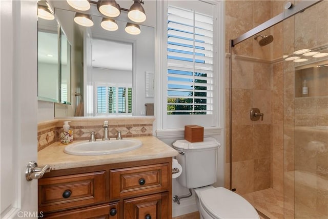 bathroom featuring toilet, a shower with shower door, backsplash, and vanity