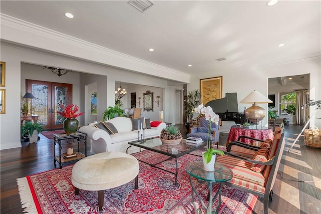 living room featuring dark hardwood / wood-style flooring, ornamental molding, french doors, and an inviting chandelier