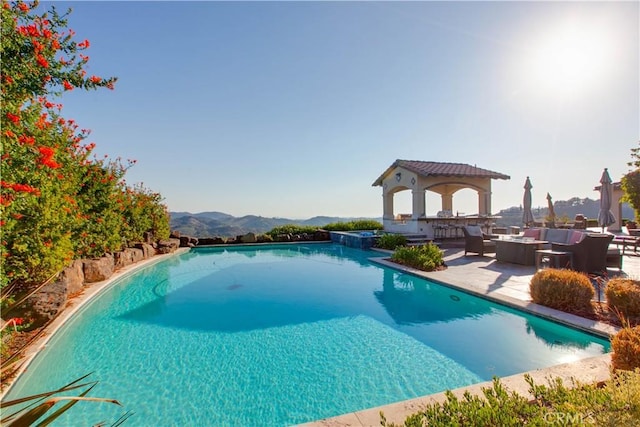 view of swimming pool featuring an outdoor hangout area, a gazebo, a mountain view, and a patio