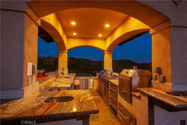 patio at night featuring sink, a mountain view, grilling area, and area for grilling