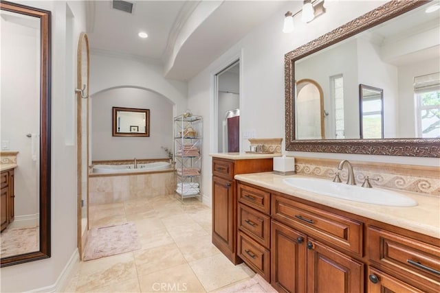 bathroom featuring tiled bath, ornamental molding, and vanity