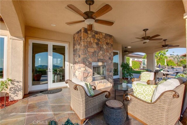 view of patio / terrace with ceiling fan, an outdoor stone fireplace, and french doors