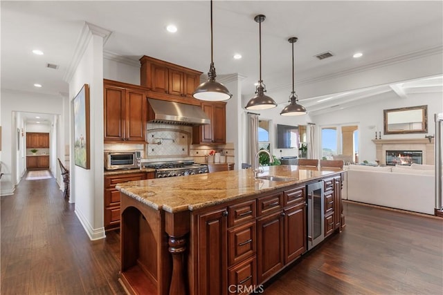 kitchen with wine cooler, decorative backsplash, sink, an island with sink, and ventilation hood