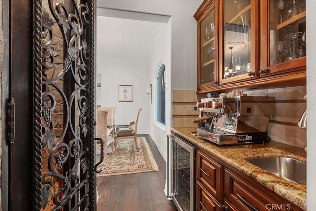 bar with decorative backsplash, dark hardwood / wood-style flooring, beverage cooler, light stone countertops, and sink