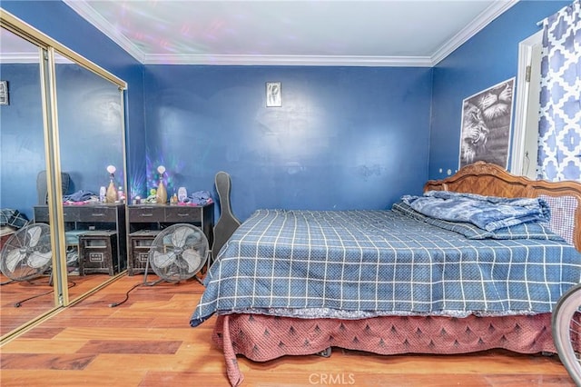 bedroom with wood-type flooring, ornamental molding, and a closet