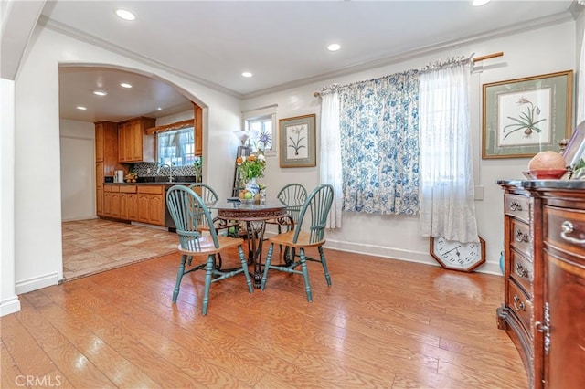 dining area with sink, light wood-type flooring, and crown molding