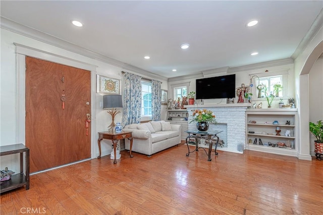 living room with crown molding, plenty of natural light, and light wood-type flooring