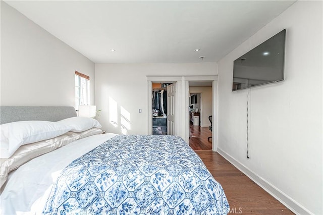 bedroom with a walk in closet, dark hardwood / wood-style floors, and a closet