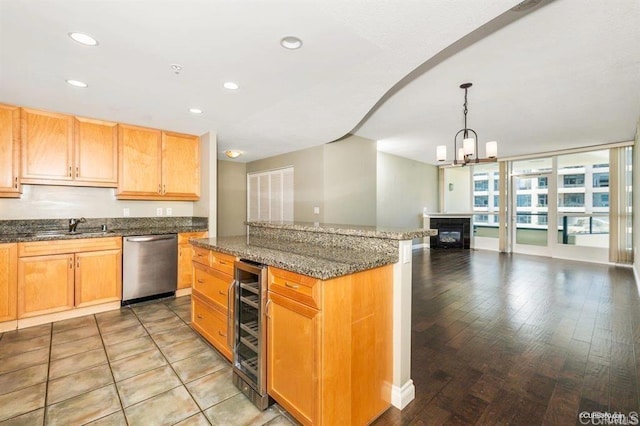 kitchen with sink, dark stone countertops, wine cooler, decorative light fixtures, and stainless steel dishwasher