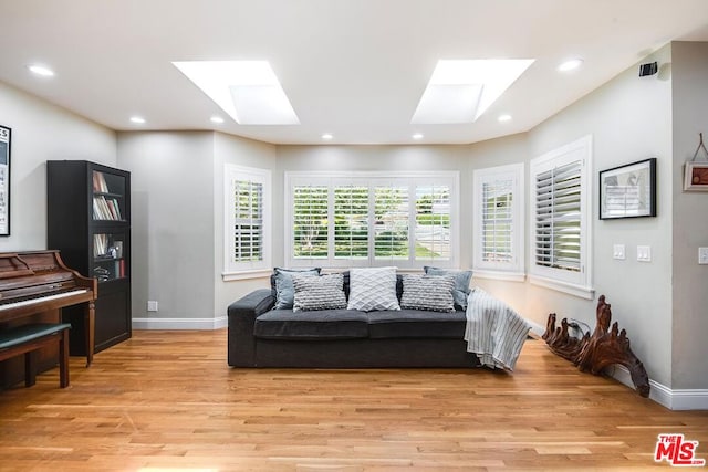 living room with light hardwood / wood-style floors, a wealth of natural light, and a skylight