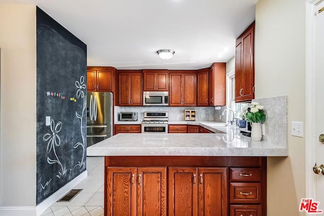 kitchen with kitchen peninsula, appliances with stainless steel finishes, light tile patterned floors, and sink