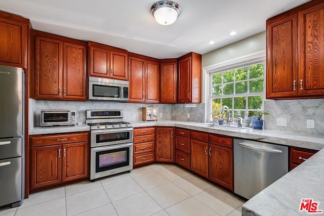 kitchen featuring light tile patterned floors, backsplash, stainless steel appliances, and sink