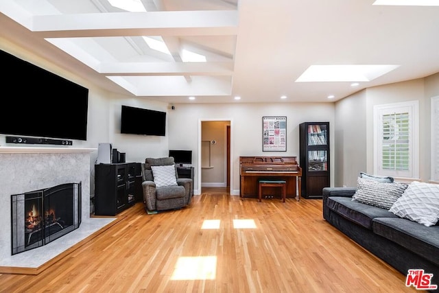 living room with beamed ceiling, light hardwood / wood-style floors, and a skylight