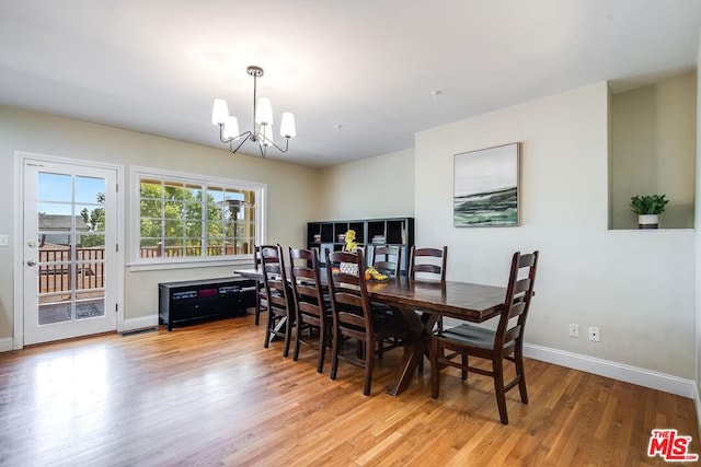 dining area with light hardwood / wood-style floors and an inviting chandelier