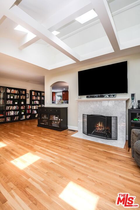 living room featuring beam ceiling, a fireplace, and hardwood / wood-style flooring