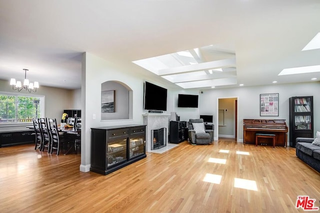 living room with hardwood / wood-style flooring, an inviting chandelier, a high end fireplace, and a skylight