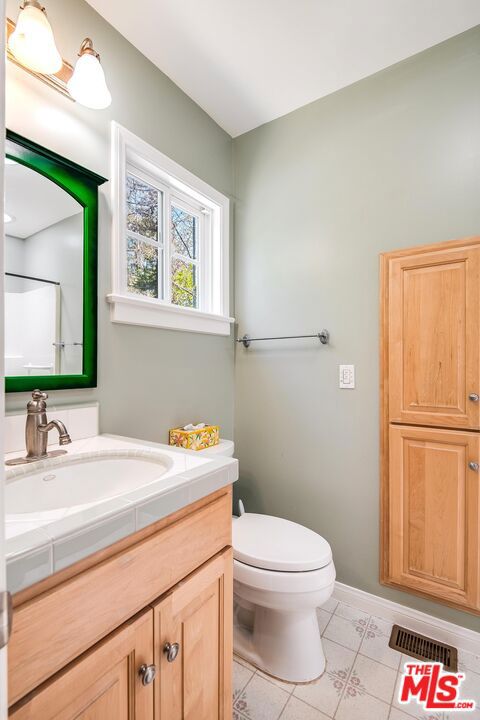 bathroom featuring tile patterned flooring, a shower, vanity, and toilet