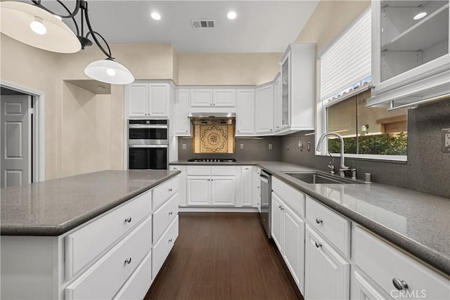 kitchen with backsplash, sink, hanging light fixtures, appliances with stainless steel finishes, and white cabinetry