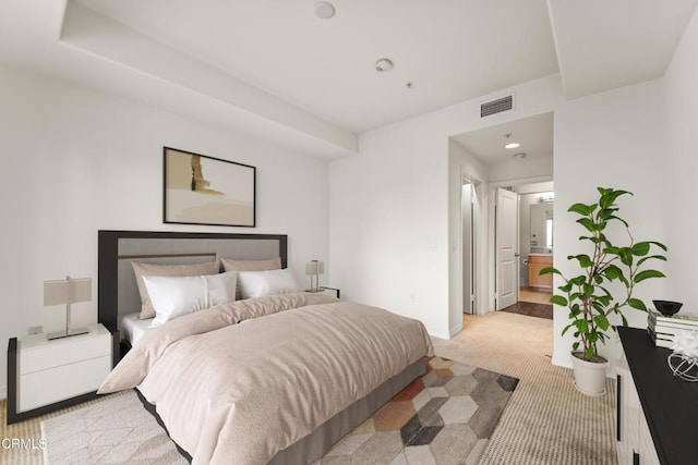 bedroom featuring light carpet and ensuite bath