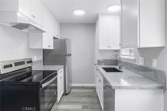 kitchen featuring appliances with stainless steel finishes, sink, white cabinetry, light hardwood / wood-style floors, and light stone counters