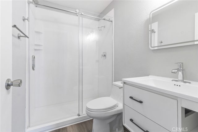 bathroom featuring vanity, toilet, a shower with door, and hardwood / wood-style floors