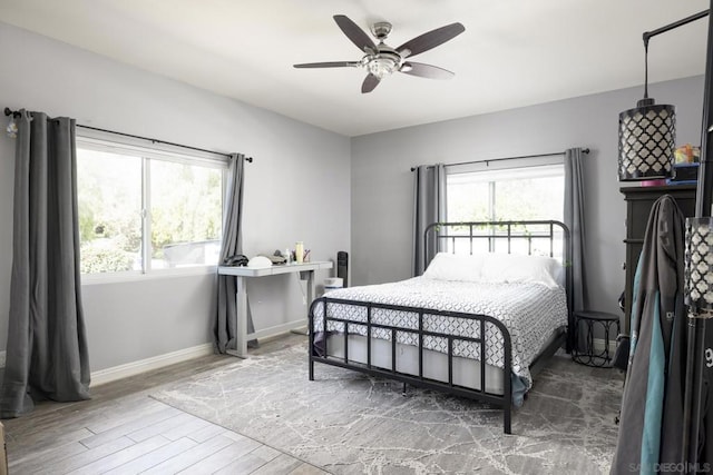 bedroom featuring ceiling fan, wood-type flooring, and multiple windows