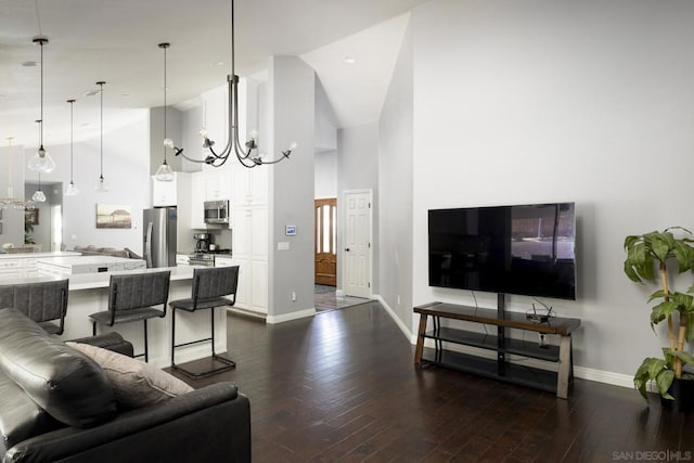 living room with high vaulted ceiling, dark hardwood / wood-style floors, and an inviting chandelier