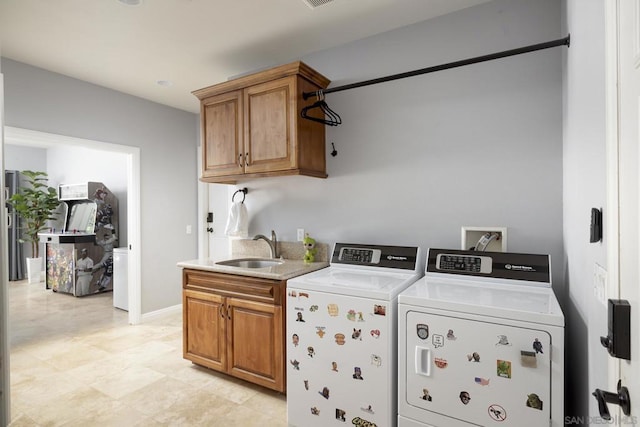 clothes washing area featuring washing machine and dryer, sink, and cabinets