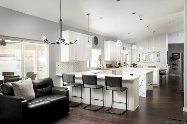 kitchen featuring kitchen peninsula, a breakfast bar area, tasteful backsplash, vaulted ceiling, and white cabinets