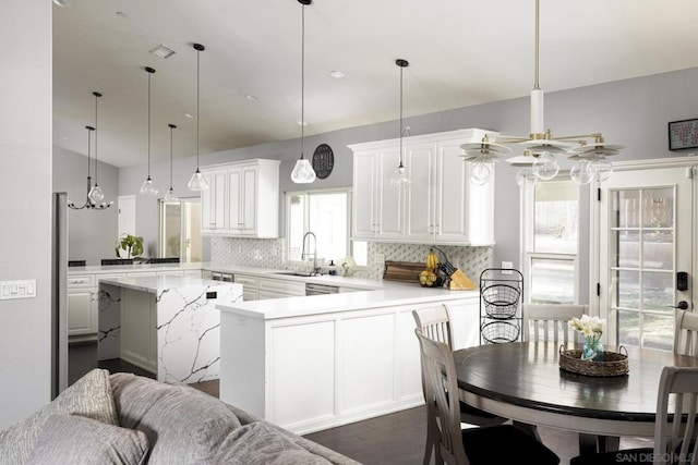 kitchen with tasteful backsplash, kitchen peninsula, sink, and decorative light fixtures