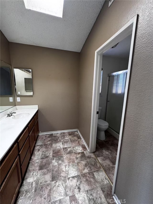 bathroom featuring toilet, vanity, a skylight, and a textured ceiling