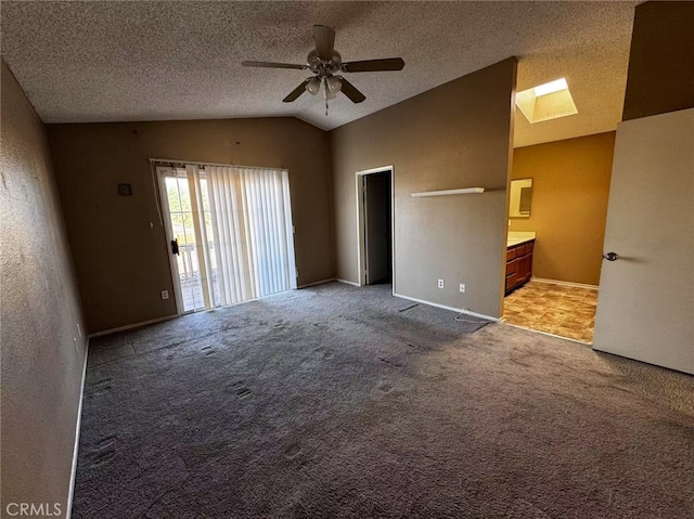 unfurnished room with a textured ceiling, ceiling fan, vaulted ceiling with skylight, and light colored carpet