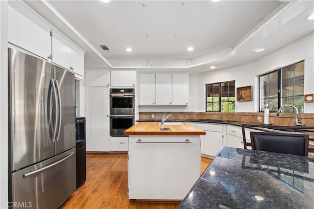 kitchen featuring a kitchen island, butcher block countertops, sink, appliances with stainless steel finishes, and white cabinets