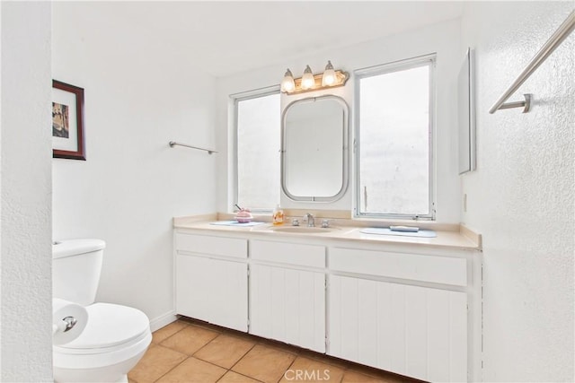 bathroom with toilet, vanity, and tile patterned flooring