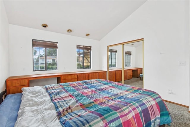 bedroom with built in desk, lofted ceiling, a closet, and carpet flooring