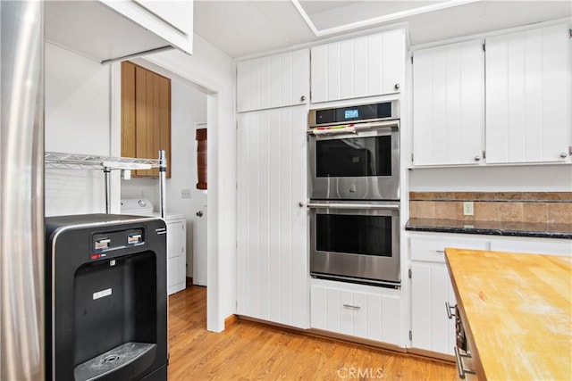 kitchen featuring washer / dryer, light hardwood / wood-style floors, white cabinets, and stainless steel double oven