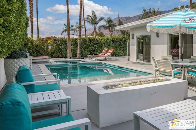 view of swimming pool featuring a mountain view, an outdoor fire pit, an in ground hot tub, and a patio