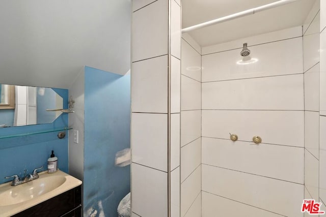 bathroom with a tile shower and vanity