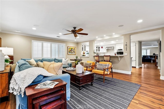 living room with crown molding, plenty of natural light, ceiling fan, and hardwood / wood-style flooring