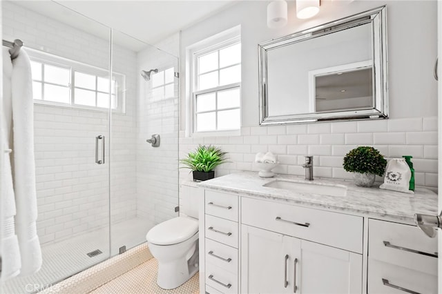 bathroom with tile walls, vanity, toilet, a shower with door, and tile patterned floors