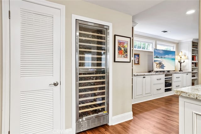 bar with wine cooler, light stone countertops, dark wood-type flooring, and white cabinets