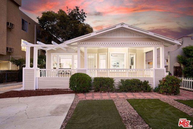 view of front of home with covered porch and a yard